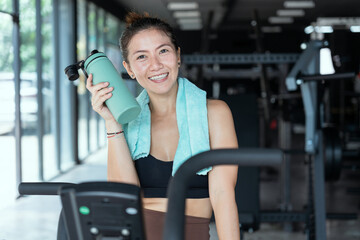 Woman exercising in outdoor gym while taking a break to hydrate on a sunny day