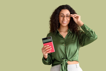 Naklejka premium Young African-American woman with calculator on green background