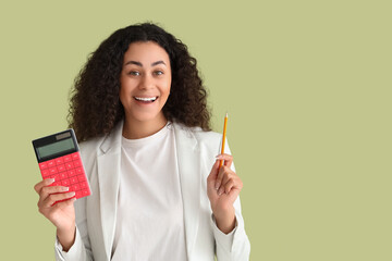 Happy African-American woman with calculator and pencil on green background