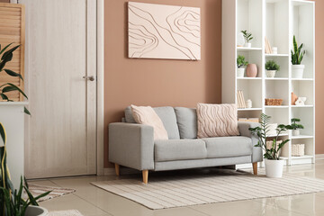 Cozy sofa, houseplant and shelving unit in interior of living room