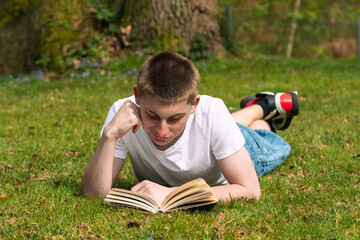 Teenage boy reading a book in a park