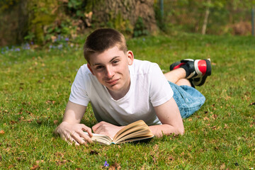 Teenage boy reading a book in a park