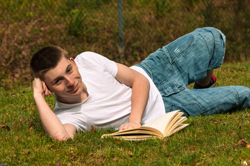 Teenage boy reading a book in a park