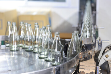 Glass bottles of purified drinking water inside drinking water or beverage factory which has automated conveyor production line. Water manufacture business. Beverages industry business.