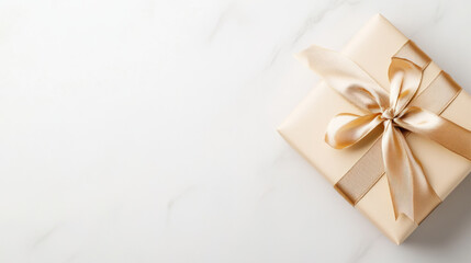 Elegant gold-wrapped gift box with satin ribbon on marble surface