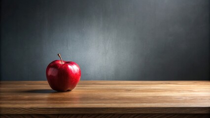 A solitary red apple rests on a rustic wooden surface against a dark gray backdrop