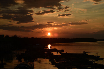 Sunset over Calm Water: A fiery sunset paints the sky with vibrant oranges and reds, casting a warm...