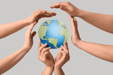 Female hands with paper Earth on light background. Ecology concept