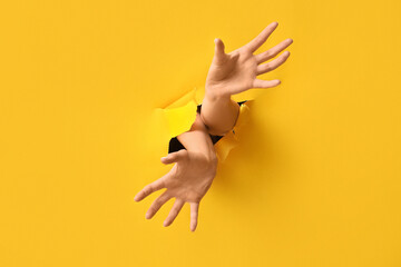 Female hands visible through hole in yellow paper