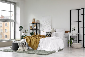 Interior of light bedroom with folding screen, bookshelf and table © Pixel-Shot