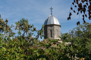 Orthodox Church is Church of Iverskaya Our Lady or Armenian Church as Church of John Baptist. Church dome with cross atop, surrounded by lush greenery and  clear blue sky.