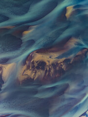 erial abstract view of Icelandic river delta patterns at low tide, with vivid blue and golden tones blending in smooth organic shapes. Nature’s art captured from above.