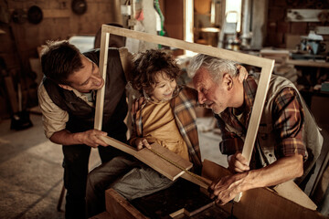 Happy grandfather teaching grandson carpentry with father in workshop