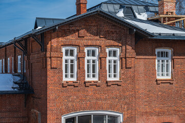 Facade of old brick house with windows at sunny spring day.