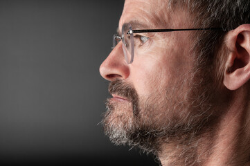Obraz premium Portrait of senior bearded man in eyeglasses on a black background