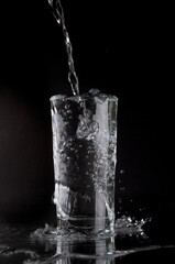 Pouring soda water into glass on a black background