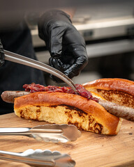 Chef preparing american hot dog by adding filling