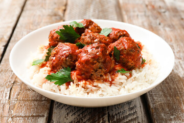 Tasty meatballs with sauce and rice on wooden table, closeup