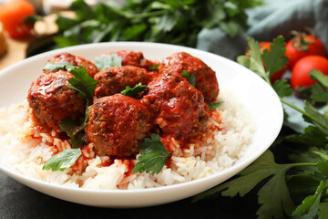 Tasty meatballs with sauce, rice and products on black table, closeup