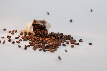 Coffee beans pouring out of a bag onto a clean white surface.
