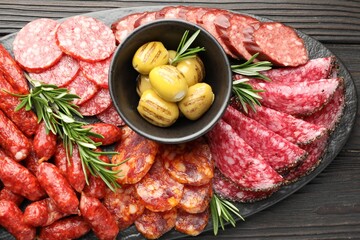 Different smoked sausages, olives and rosemary on wooden table, top view