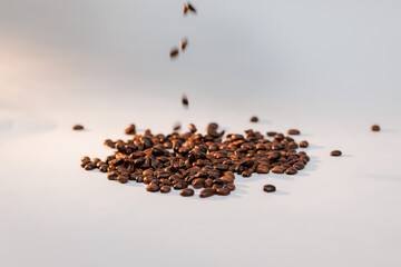 A rich pile of dark roasted coffee beans spread across a clean white surface — ideal for cafés, branding, or product promotion.