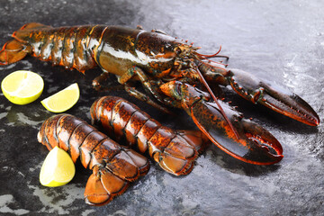 Raw lobster, tails and lime on dark table