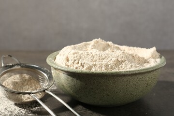 Brown rice flour and sieve on grey table, closeup