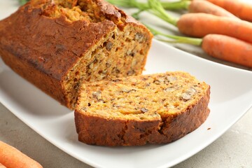 Homemade carrot cake with nuts and vegetables on light grey table, closeup