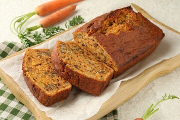 Homemade carrot cake with nuts and vegetables on white textured table, closeup