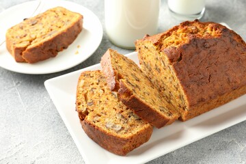 Cut homemade carrot cake with nuts and milk on grey table, closeup