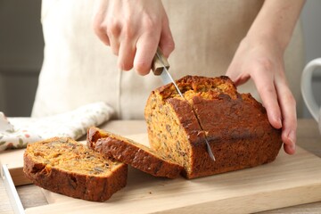 Woman cutting homemade carrot cake at table, closeup