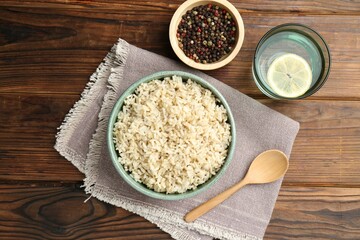 Delicious brown rice served on wooden table, flat lay