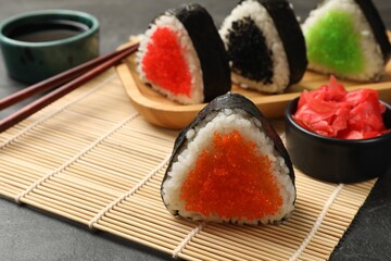 Tasty tobiko onigiri (Japanese rice balls) served on black table, closeup