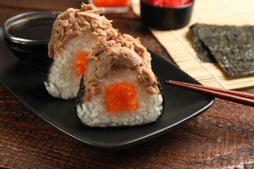 Tasty onigiri (Japanese rice balls) with tuna served on wooden table, closeup