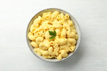 Delicious pasta with cheese sauce in bowl on light table, top view