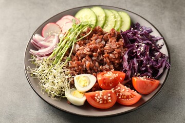 Tasty salad with brown rice on grey table, closeup