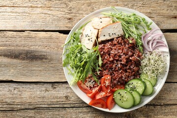 Delicious salad with brown rice on wooden table, top view