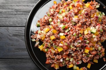 Tasty salad with brown rice on black wooden table, top view