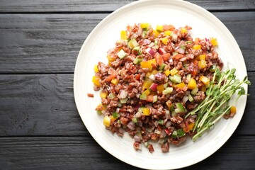 Tasty salad with brown rice on black wooden table, top view. Space for text