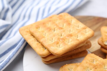 Tasty salty crackers on white table, closeup