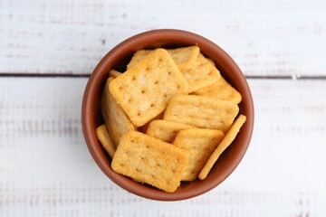 Tasty salty crackers on white wooden table, top view