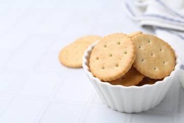 Tasty salty crackers on white tiled table, closeup. Space for text