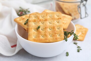 Tasty salty crackers and thyme on white table, closeup