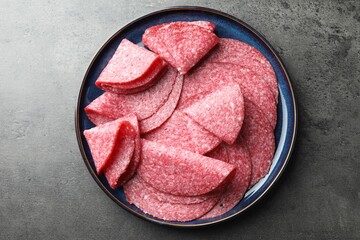 Slices of delicious sausage served on grey table, top view