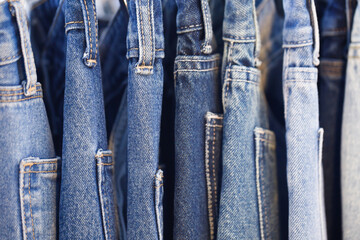 A close up of a blue denim row of jeans hanging on a rack. of different colors and styles. Concept...