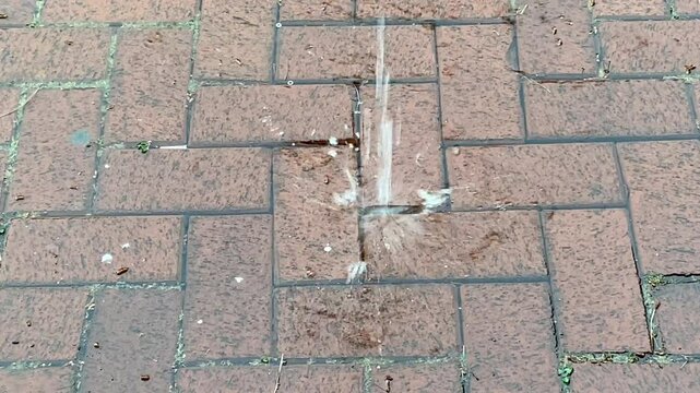 A dynamic water splash captured on a brick pavement, showing droplets in mid-air as they hit the ground. The image highlights the impact and texture of both water and surface