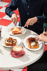 People dining in cafe with toasts and savory waffle