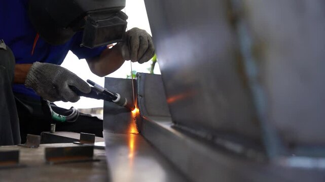 A skilled welder meticulously welds metal components, sparks flying, showcasing precision and expertise in a metalworking environment.