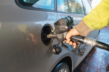 Refueling a vehicle at a service station on a clear day with focus on gas pump and car details